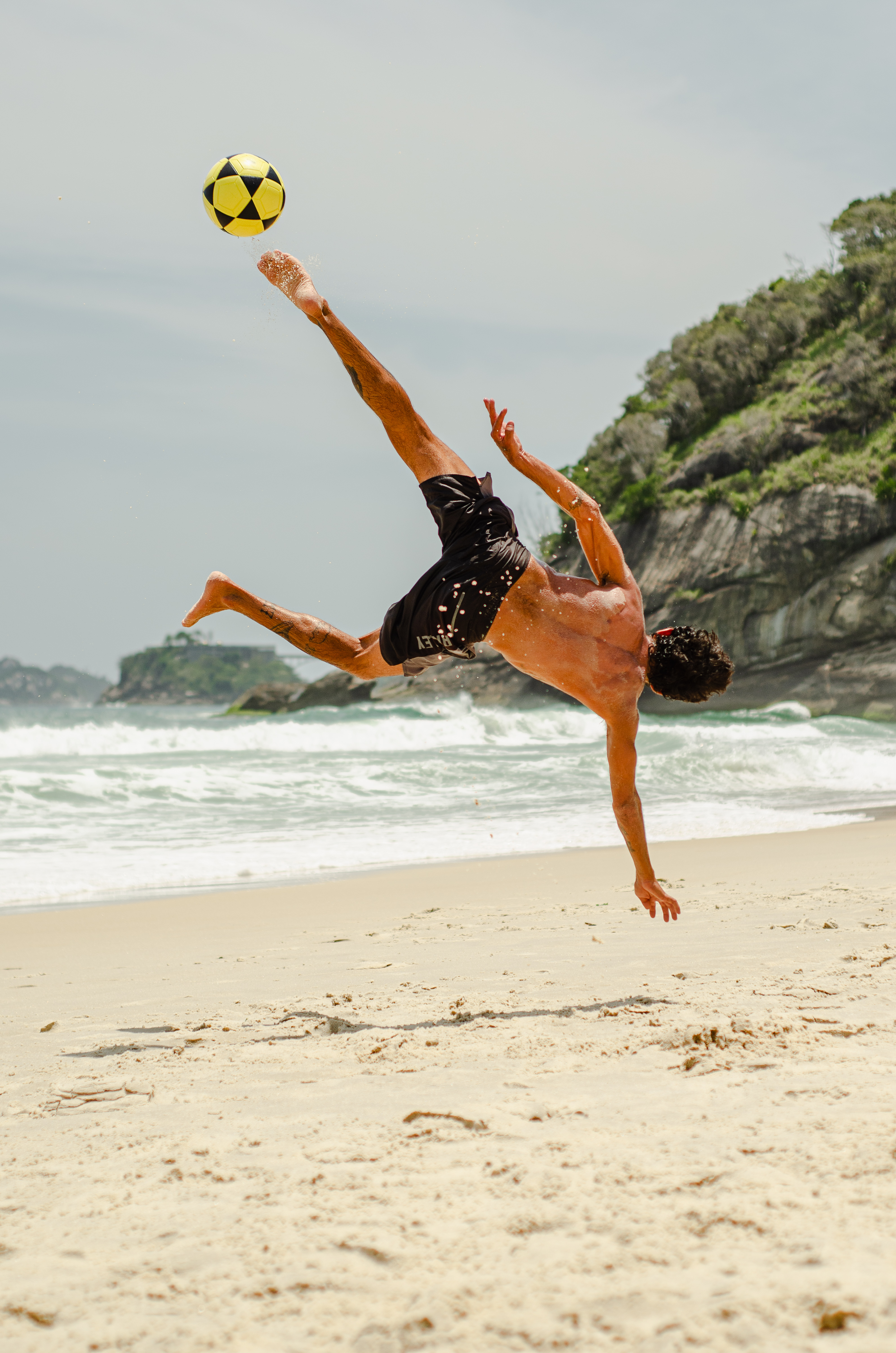 Atleta realizando um movimento acrobático na areia