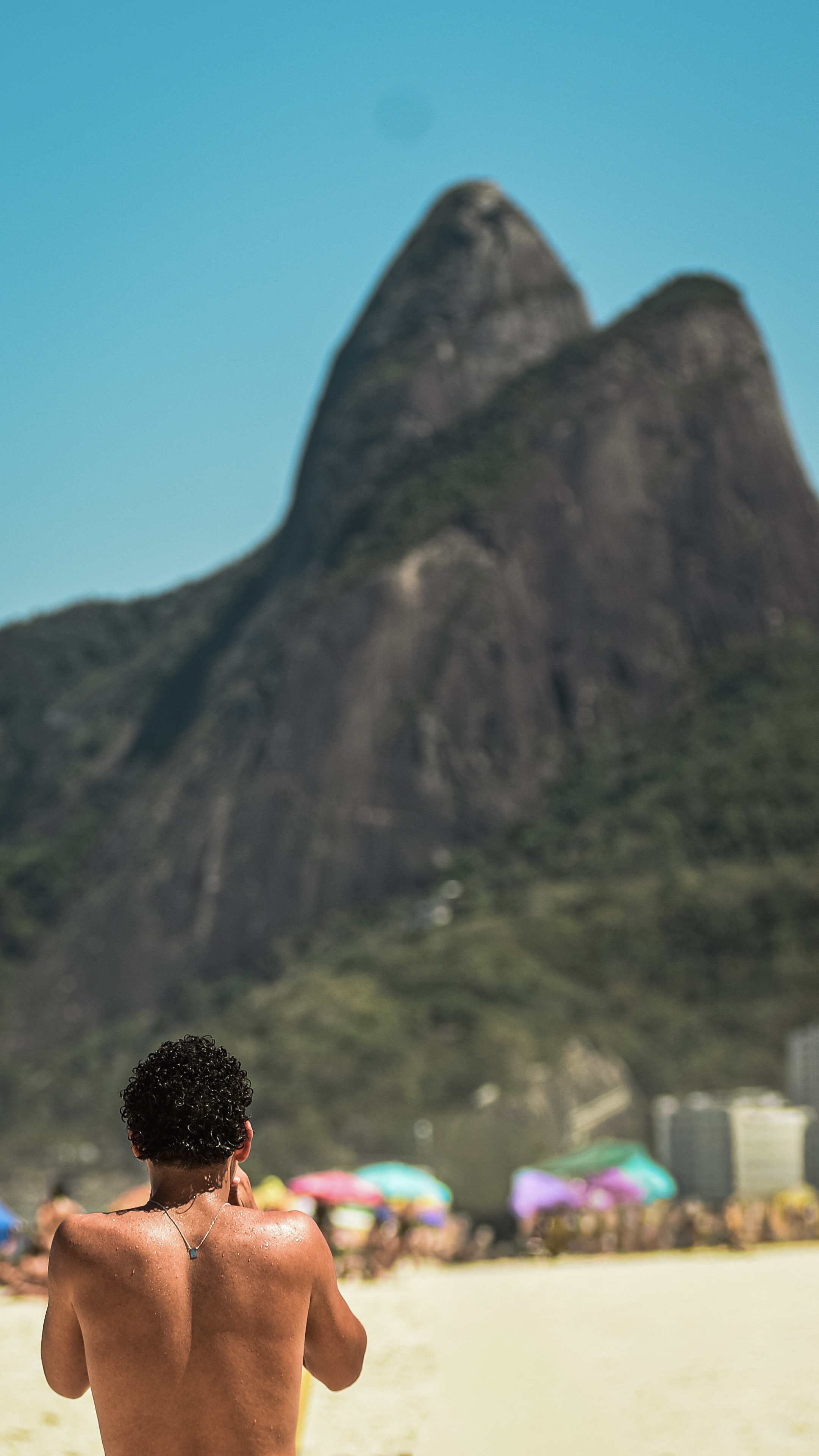 Homem observando o Morro Dois Irmãos na praia